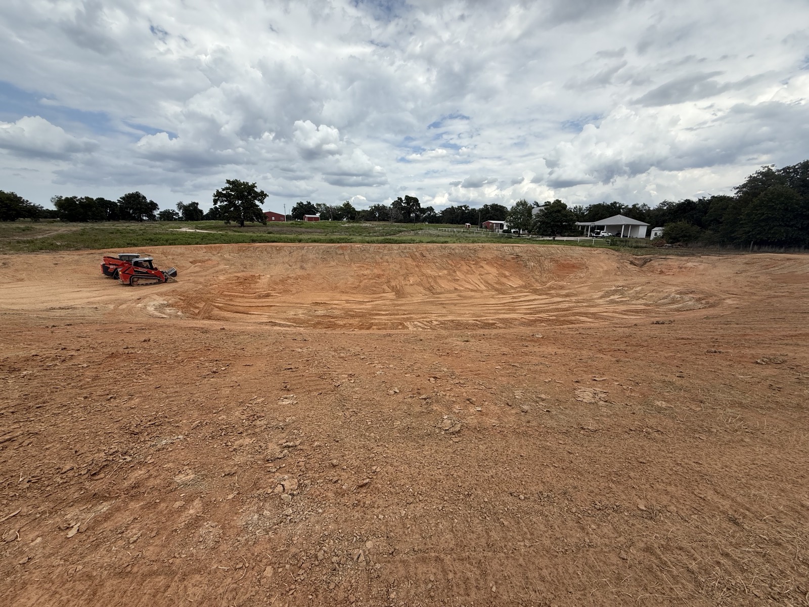 Pond basin regraded clean, compact track loader working the slope
